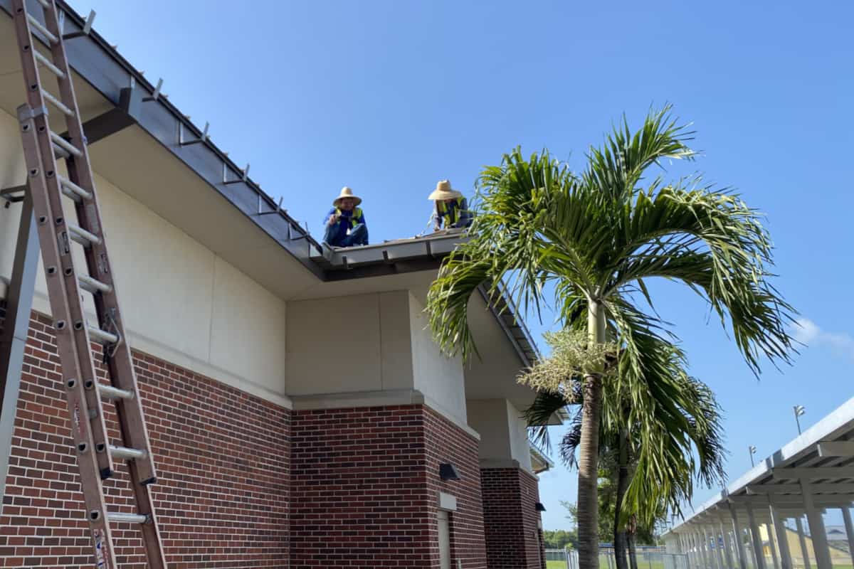 Roof being repaired by workers on the roof.